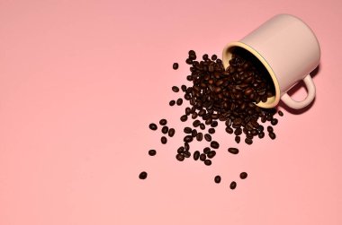 Pembe arka planda kahve çekirdekleri olan pembe bir bardak.