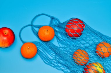 Sağlıklı yiyeceklerle dolu bir alışveriş çantası. Moda mavi arka planda farklı meyvelerden yapılmış özel tasarım el çantasının yemek fotoğrafçılığı. 2020 yılının klasik mavi rengi