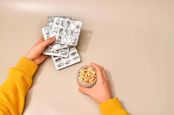 Hands with pharmaceuticals antibiotics pills medicine. colorful antibacterials pills on beige background. capsule pill medicine. Simbol of 2020 year, cronavirus broblem