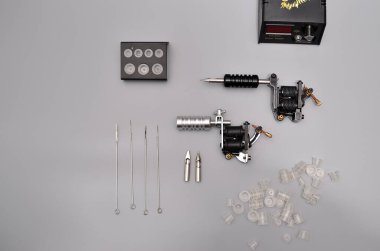 Dövme makineleri, iğneler ve gri arka planda izole edilmiş tüm bu dövme şeyleri. Dövme silahları. Dövme makineli desen, iş tasarımınız için duvar kağıdı