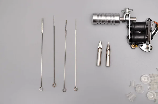 Tattoo machines, needles and all these tattoo stuff isolated on grey background. Tattoo guns. Pattern with tattoo machine, wallpaper for your business design