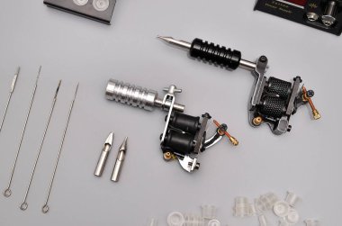 Dövme makineleri, iğneler ve gri arka planda izole edilmiş tüm bu dövme şeyleri. Dövme silahları. Dövme makineli desen, iş tasarımınız için duvar kağıdı