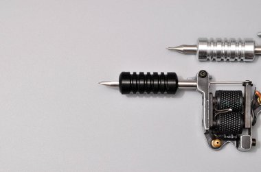 Dövme makineleri, iğneler ve gri arka planda izole edilmiş tüm bu dövme şeyleri. Dövme silahları. Dövme makineli desen, iş tasarımınız için duvar kağıdı