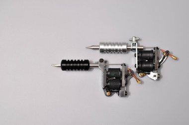 Dövme makineleri, iğneler ve gri arka planda izole edilmiş tüm bu dövme şeyleri. Dövme silahları. Dövme makineli desen, iş tasarımınız için duvar kağıdı