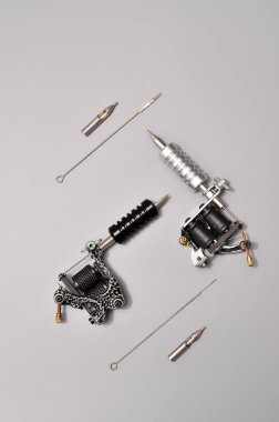 Dövme makineleri, iğneler ve gri arka planda izole edilmiş tüm bu dövme şeyleri. Dövme silahları. Dövme makineli desen, iş tasarımınız için duvar kağıdı