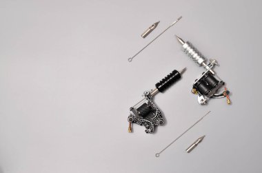 Dövme makineleri, iğneler ve gri arka planda izole edilmiş tüm bu dövme şeyleri. Dövme silahları. Dövme makineli desen, iş tasarımınız için duvar kağıdı