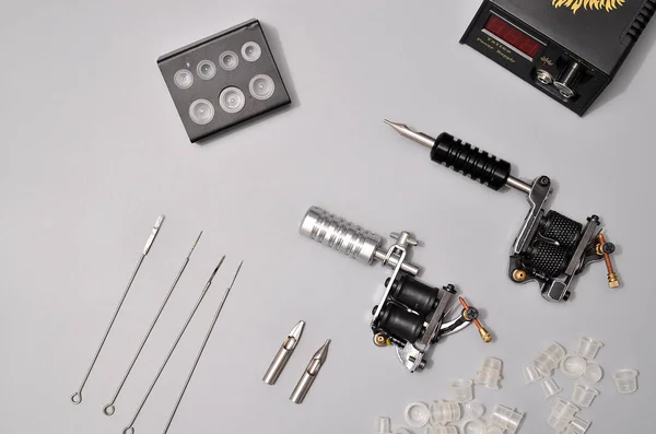 Tattoo machines, needles and all these tattoo stuff isolated on grey background. Tattoo guns. Pattern with tattoo machine, wallpaper for your business design
