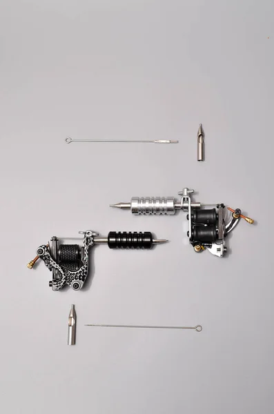 Tattoo machines, needles and all these tattoo stuff isolated on grey background. Tattoo guns. Pattern with tattoo machine, wallpaper for your business design