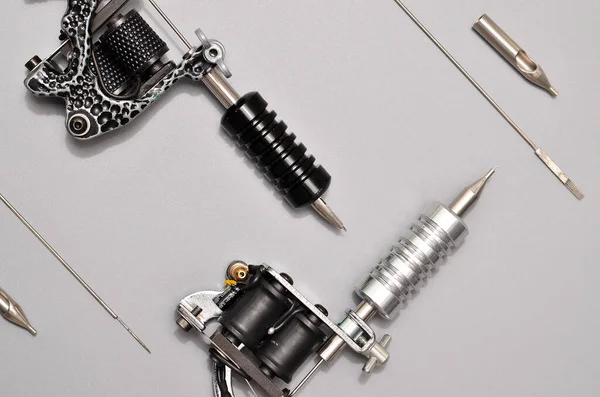 Tattoo machines, needles and all these tattoo stuff isolated on grey background. Tattoo guns. Pattern with tattoo machine, wallpaper for your business design