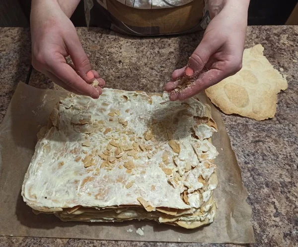 Mujer confitero asperja pastel en la cocina —  Fotos de Stock