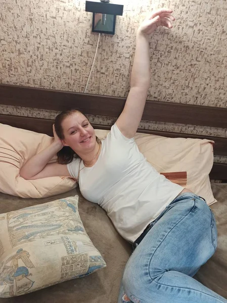 Счастливая европейская женщина лежит на кровати дома — стоковое фото