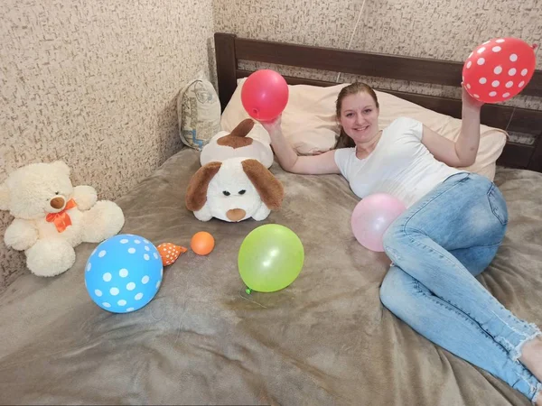 Счастливая женщина лежит на кровати с воздушными шарами — стоковое фото
