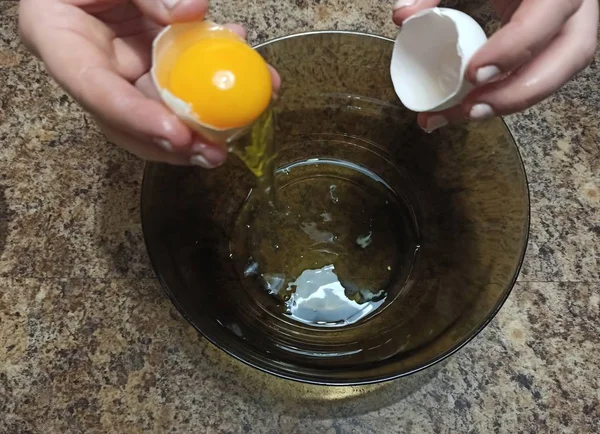 Woman confectioner breaks egg in bowl — Stock Photo, Image