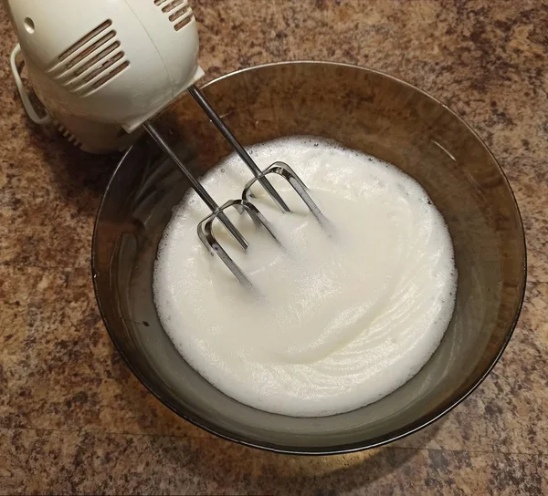 Mélangeur dans un bol avec bizet pour gâteau sur table de cuisine — Photo