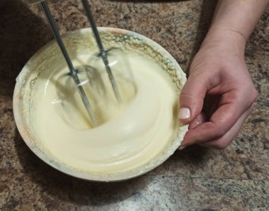 Kadın kremayla kaseyi karıştırıyor.