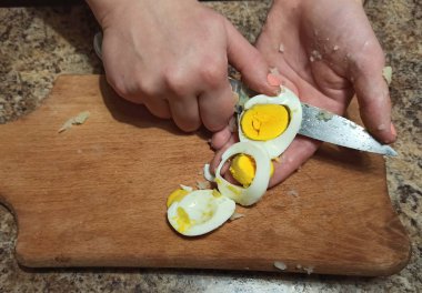 Kadın aşçı kesme tahtasında yumurta kesiyor.