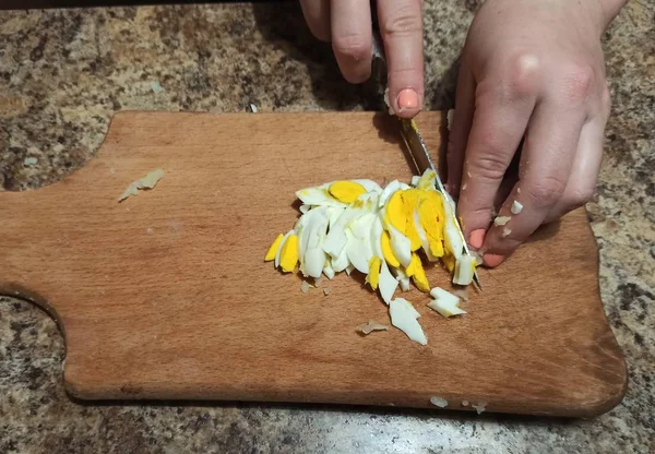 Woman cook cut egg on cutting board — Stock Photo, Image