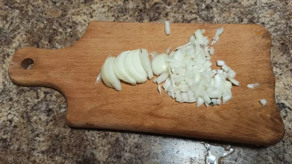 Hagyma szeletek vágódeszkán a konyhaasztalon — Stock Fotó