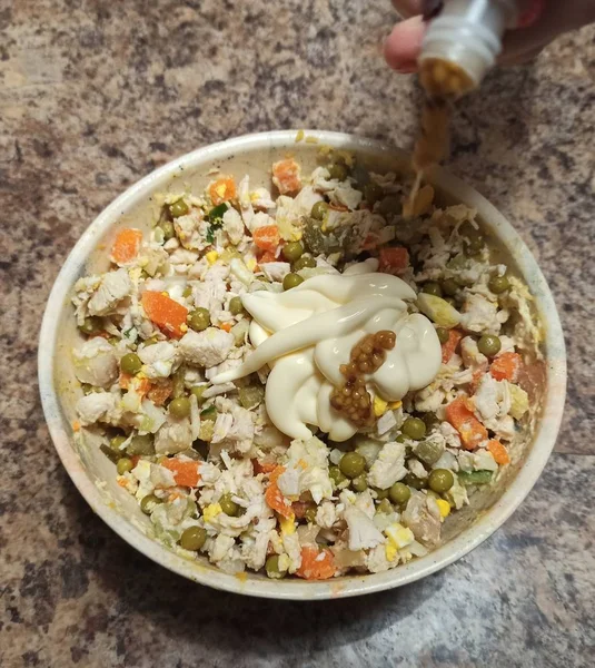 Mulher cozinheiro despeje mostarda para tigela com salada — Fotografia de Stock