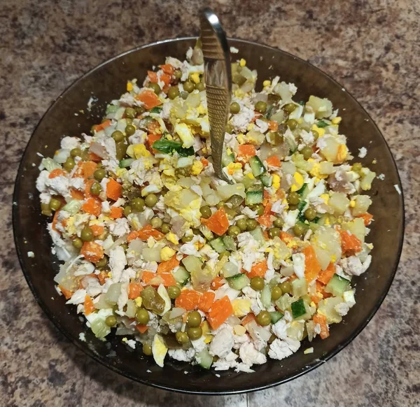Schüssel mit russischem Salat und Löffel auf Küchentisch — Stockfoto