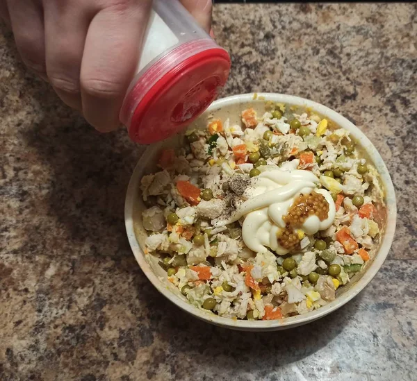 Mujer cocinar verter sal al tazón con ensalada —  Fotos de Stock