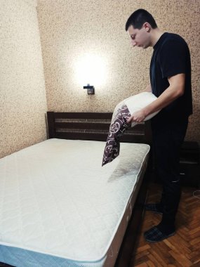 Avrupalı adam yatak odasındaki yastığın üzerine yastık kılıfı koydu.