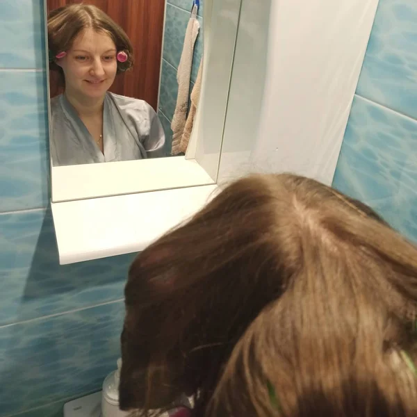 Vrouw met haar krulspelden in haar look in spiegel — Stockfoto