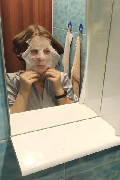 Европейская женщина наносит маску на лицо в ванной комнате — стоковое фото