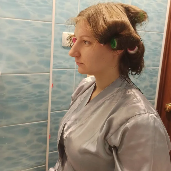 Vrouw met haar krulspelden in haar in badkamer — Stockfoto