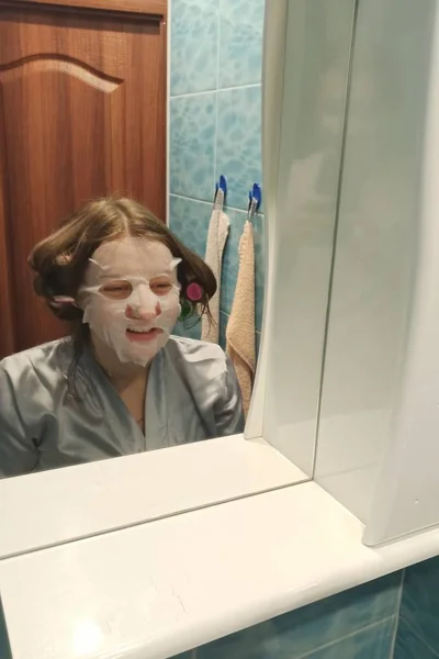 Woman look in mirror on her face with face mask — 스톡 사진