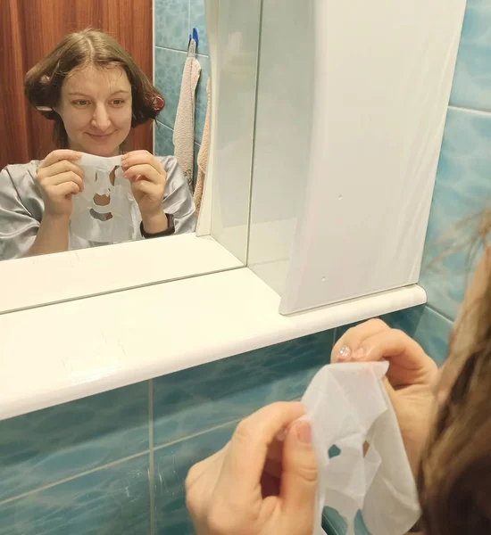 European woman hold face mask at bathroom — 스톡 사진