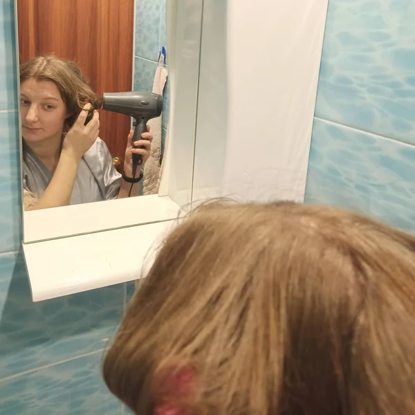 Сухие волосы европейской женщины с феном в ванной комнате — стоковое фото