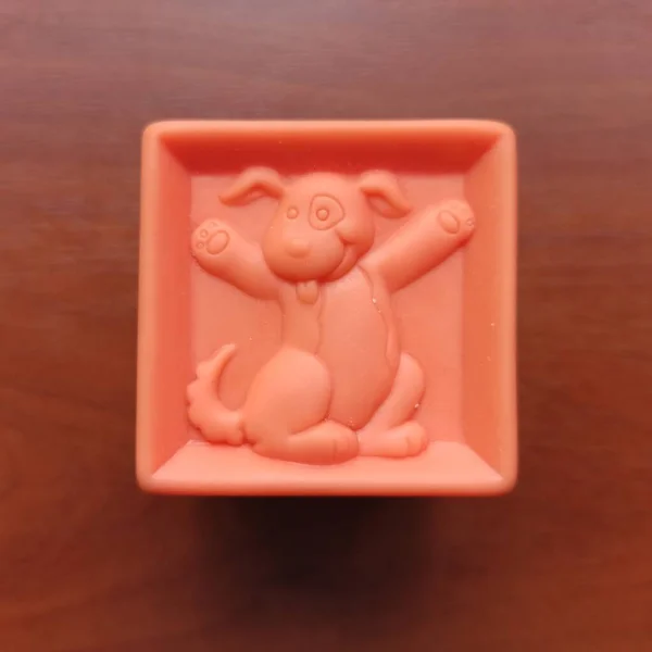 Orange toy cube with dog on wooden background