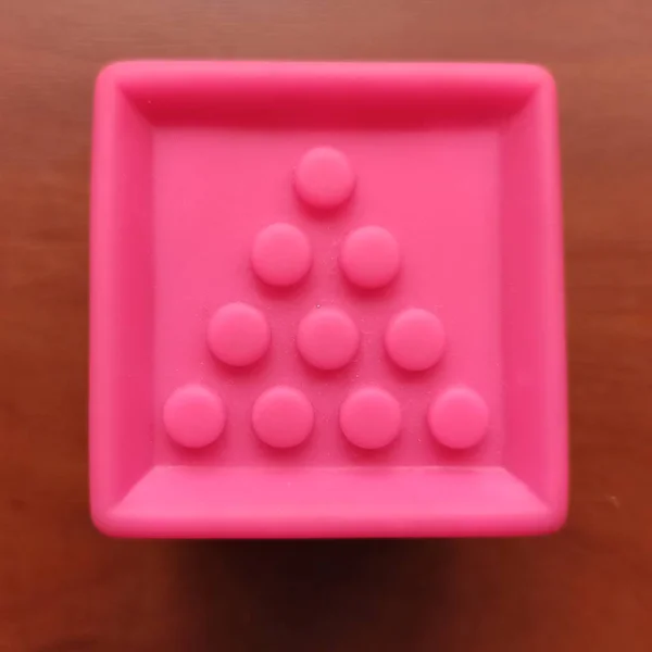 Pink toy cube with circles on wooden background — Stockfoto