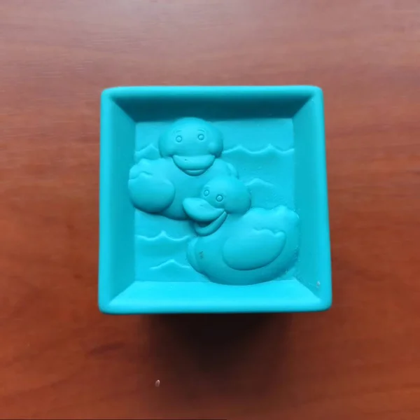 Cubo de brinquedo azul com patos no fundo de madeira — Fotografia de Stock