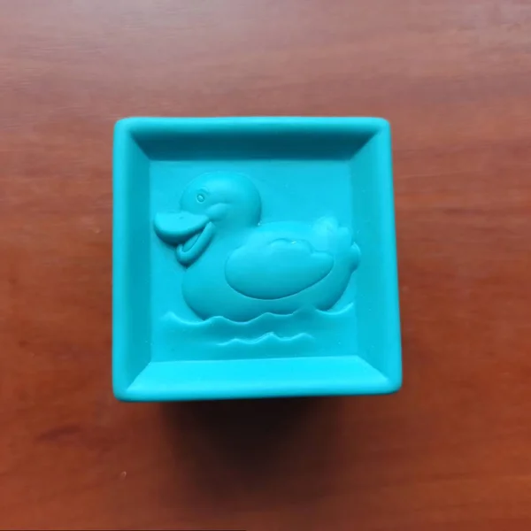Cubo de juguete azul con pato sobre fondo de madera — Foto de Stock