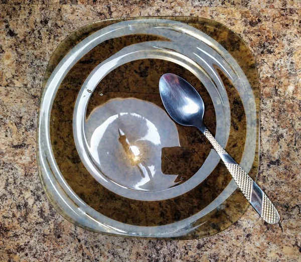 Plate with spoon on kitchen table background — ストック写真