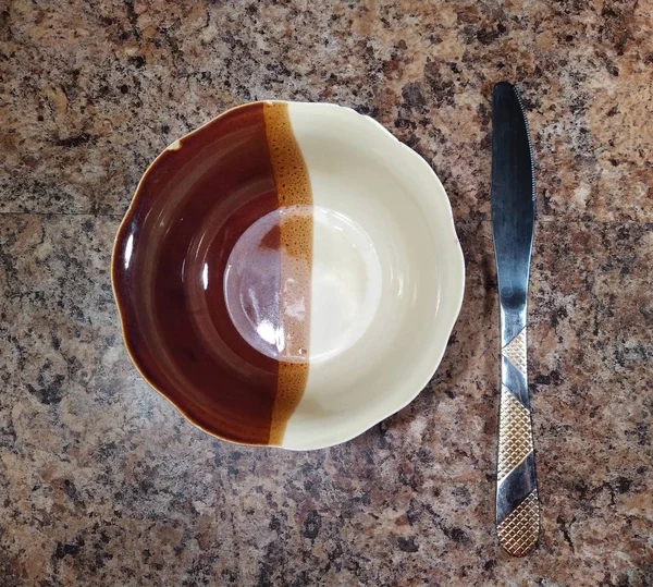 Bowl with knife on kitchen table background — Stok fotoğraf