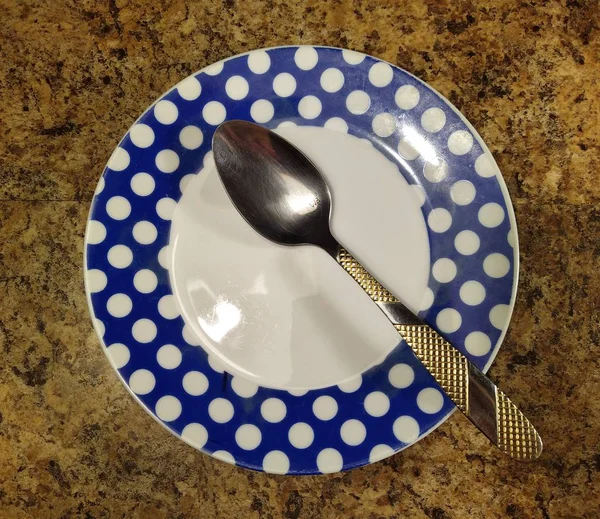 Plate with spoon on kitchen table background — Stockfoto