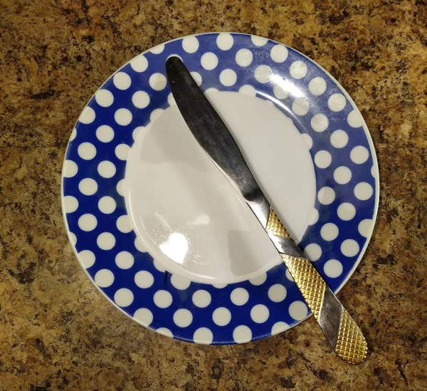 Тарілка з ножем на фоні кухонного столу — стокове фото