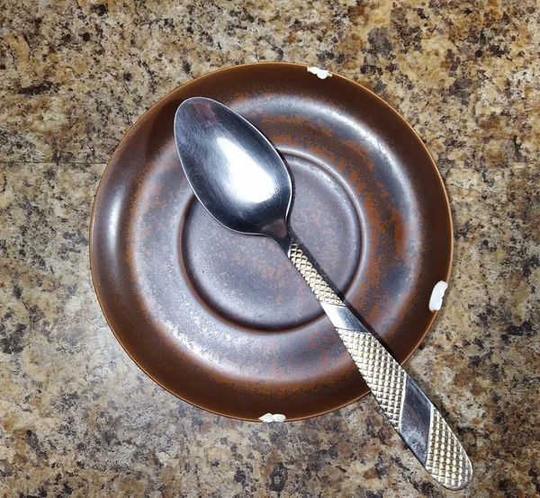 Piatto con cucchiaio su sfondo tavolo da cucina — Foto Stock
