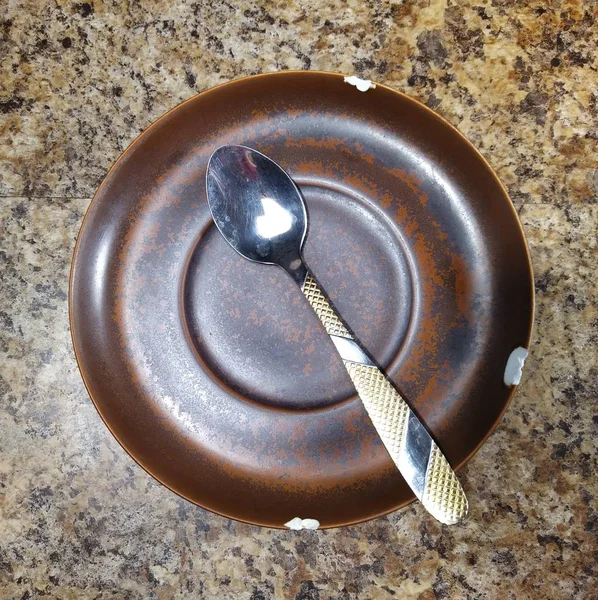 Plate with teaspoon on kitchen table background — Stok fotoğraf