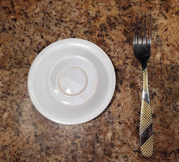 Plate with fork on kitchen table background — Stock Photo, Image