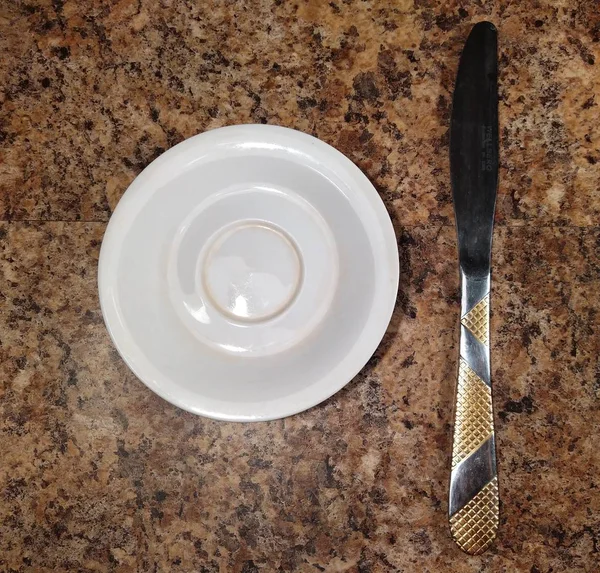 Talíř s nožem na pozadí kuchyňského stolu — Stock fotografie