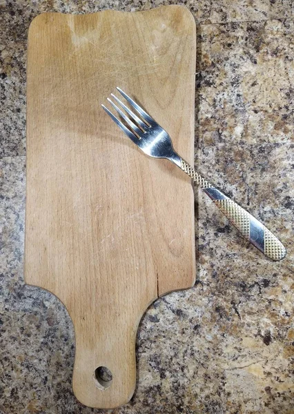 Placa de corte com garfo na mesa da cozinha — Fotografia de Stock