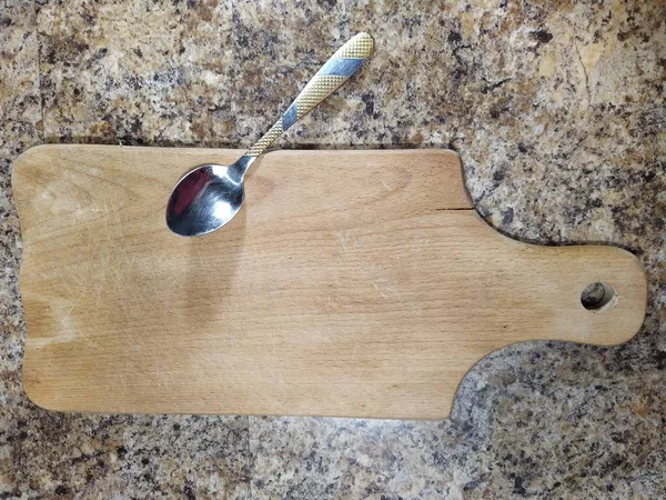 Cutting board with teaspoon on kitchen table — Stock Photo, Image