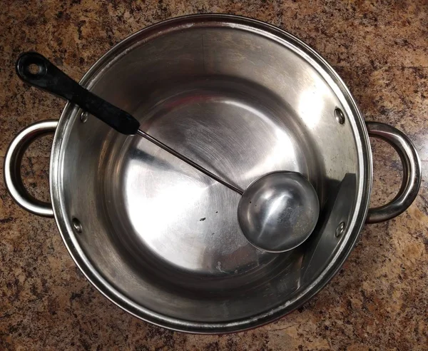 Panela com colher de cozinha na mesa da cozinha — Fotografia de Stock