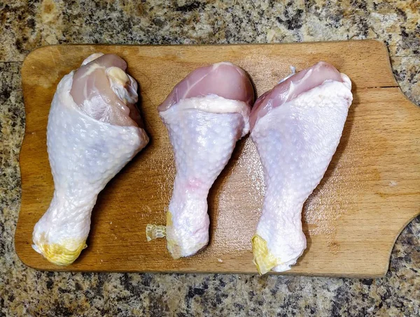 キッチンテーブルの上のまな板の上に3本の鶏の足 — ストック写真