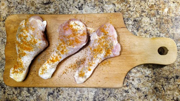 キッチンテーブルの上のまな板に調味料と鶏の足 — ストック写真