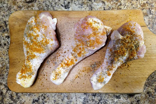 キッチンテーブルの上のまな板に調味料と鶏の足 — ストック写真